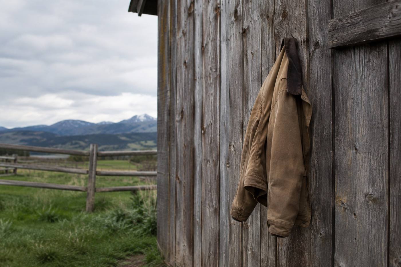 Canvas jacket hanging on a nail against a weathered barn wall