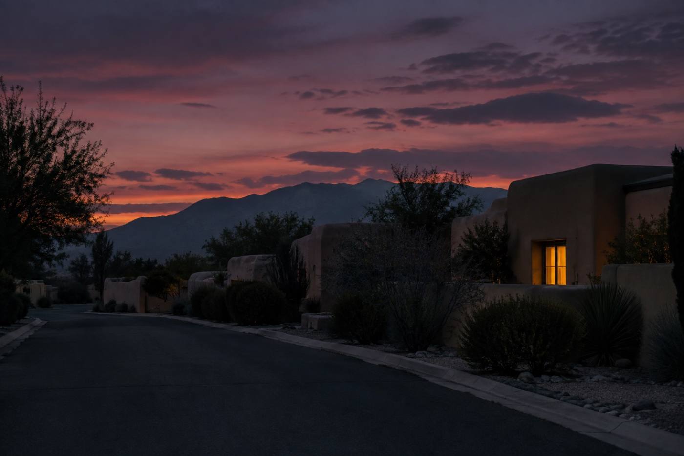 A dark residential lane at dusk with one window lit